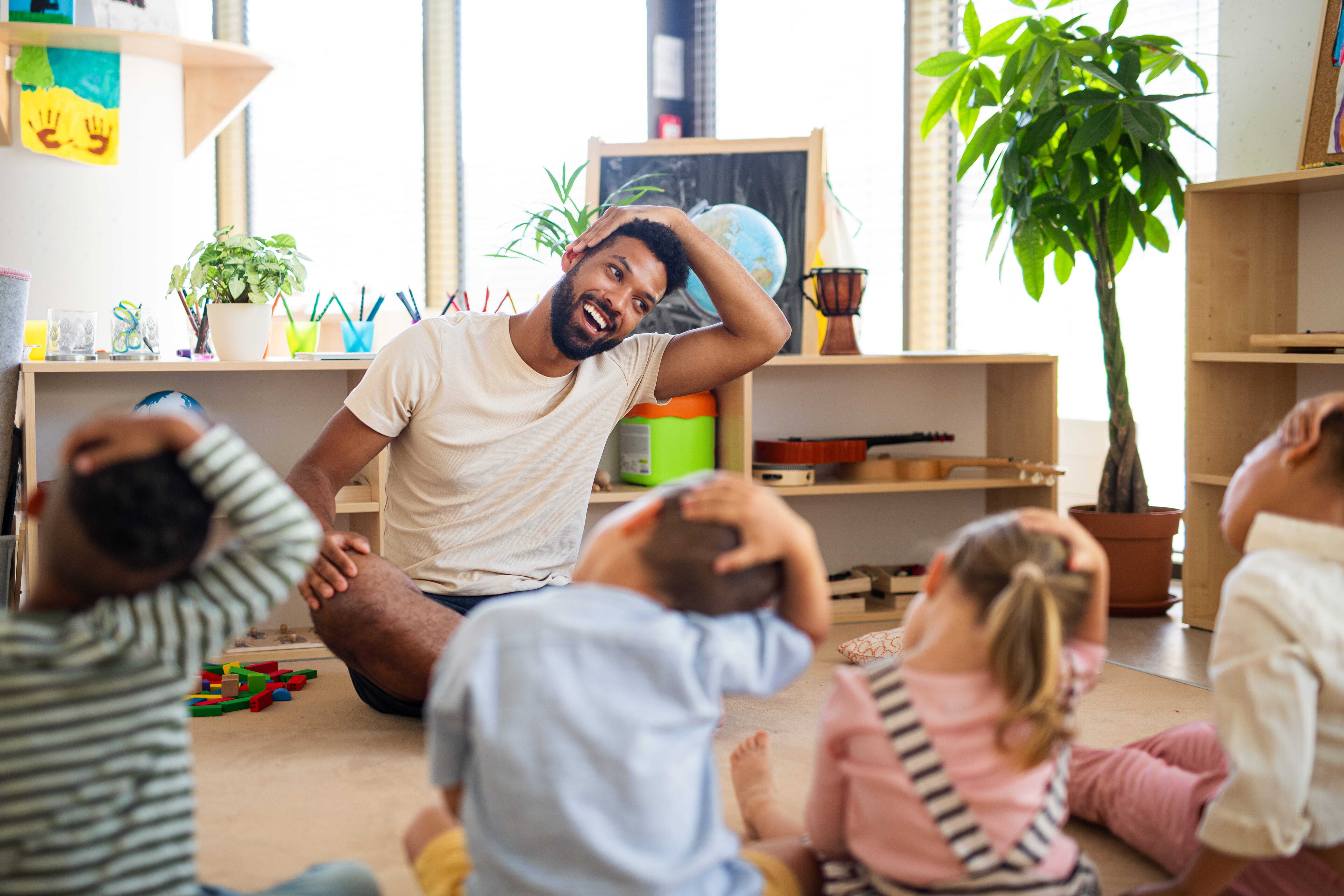 A daycare teacher practicing self-regulation with his class by stretching together.